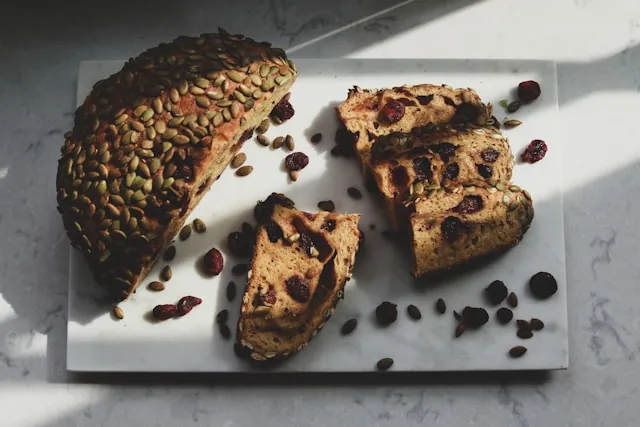 Angeschnittenes Sauerteigbrot mit Kürbiskernen und Cranberrys auf einer Marmorplatte