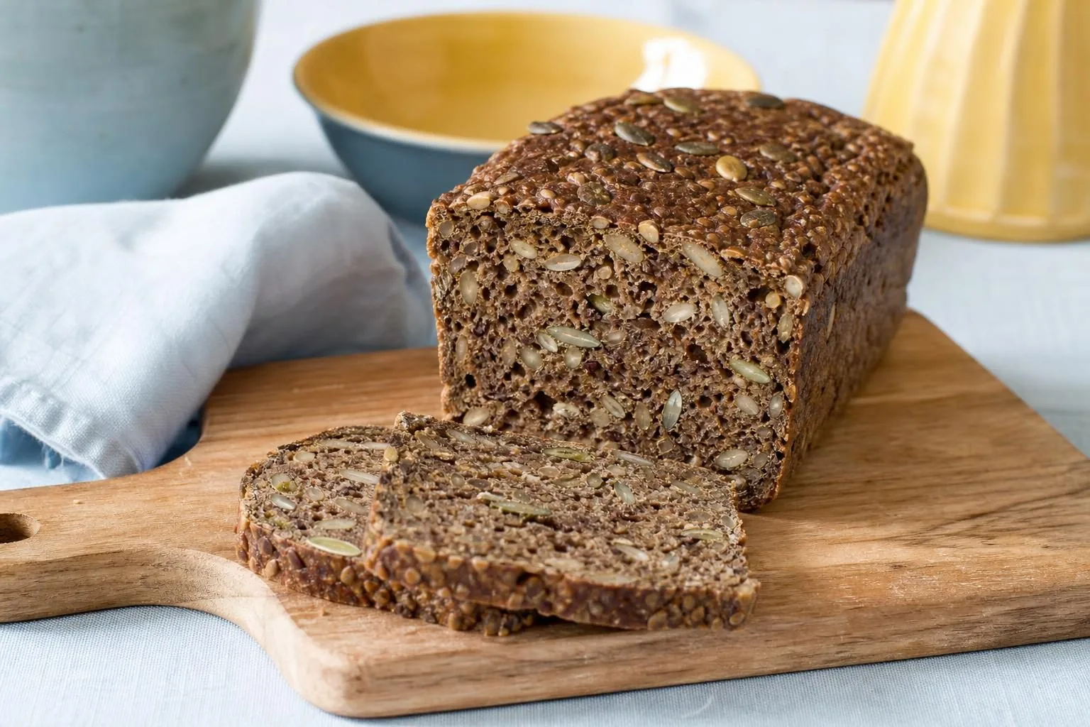 Angeschnittenes dunkles Kastenbrot mit Sonnenblumenkernen und Leinsamen in der Krume (mit AI erstelltes Bild)
